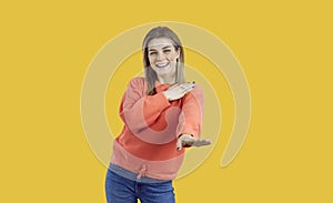 Portrait of happy beautiful young woman smiling and dancing isolated on yellow background