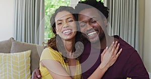 Portrait of happy biracial couple looking at camera, embracing and smiling