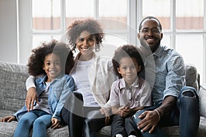 Portrait of happy biracial family with kids relax on pouch