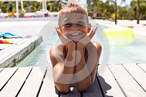 Portrait of happy biracial girl smiling by the swimming pool