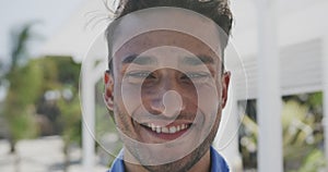 Portrait of happy biracial man smiling on sunny beach, in slow motion