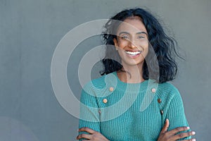 Portrait of happy biracial young female advisor with arms crossed by copy space on gray wall