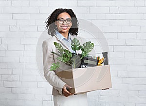 Portrait of happy black businesswoman with box of belongings starting new job at office