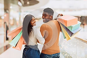 Portrait of happy black couple looking back holding shopping bags