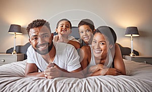Portrait of happy black family on a bed with children, carefree, relaxing and playing in a bedroom together. Young