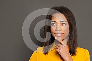 Portrait of happy black woman thinking, smiling and looking up on gray background