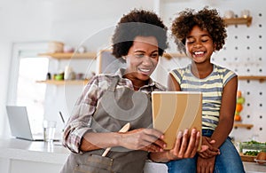 Portrait of happy black woman and her cute preteen daughter having fun together at home