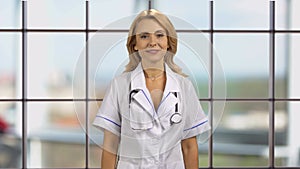 Portrait of happy blonde female doctor folds her arms.