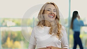 Portrait of a happy blonde woman laughing hard indoors.