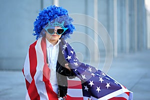 A portrait of happy boy in blue wig holding american flag.