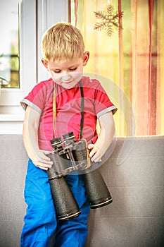Portrait of happy boy child kid playing with binoculars. At home.