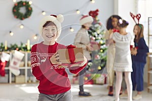 Portrait of a happy boy with a Christmas present in his hands in a room with Christmas decorations.