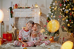 Portrait of happy boy laughing in his sister embrace on Christmas evening