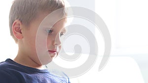 Portrait of happy boy playing with computer. Attractive kid with a laptop at home. Entertainment technology, futuristic