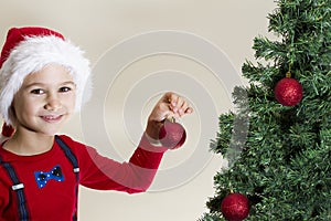 Portrait of happy boy in Santa cap decorating Christmas tree