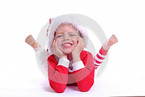 Portrait of happy boy in Santa hat and red Christmas costume lies, looks at camera and smiles. isolated on white