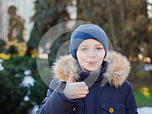 Portrait of happy boy showing thumbs up gesture, cold season