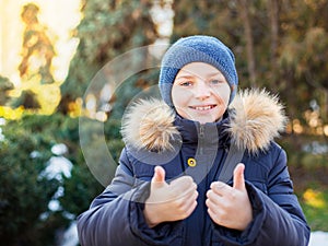 Portrait of happy boy showing thumbs up gesture and smile, cold season