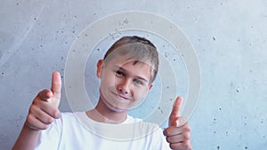 Portrait of happy boy standing and looking at camera. Kid makes gesture pointing his index finger at camera