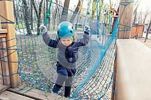 Portrait happy brave courage little toddler child boy wear safety equipment helmet enjoy passing obstacle course forest