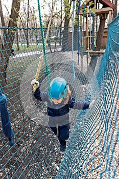 Portrait happy brave courage little toddler child boy wear safety equipment helmet enjoy passing obstacle course forest