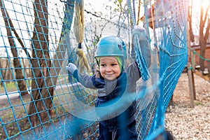 Portrait happy brave courage little toddler child boy wear safety equipment helmet enjoy passing obstacle course forest