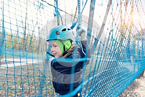 Portrait happy brave courage little toddler child boy wear safety equipment helmet enjoy passing obstacle course forest