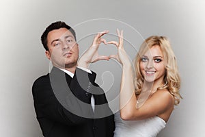 Portrait of happy bride and groom showing heart sign