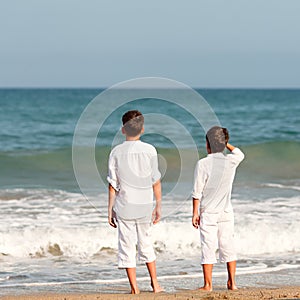 Portrait of happy brothers in white shirts on background of sea