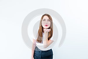 Portrait of happy brunette girl in white T-shirt sending air kiss isolated on white background. Caucasian young woman gesticulatin