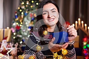 Portrait of brunette woman holding a blue gift box in hands