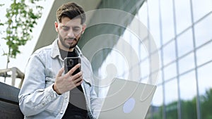 Portrait of happy business man enjoy success on mobile phone near modern office. Joyful guy reading good news on