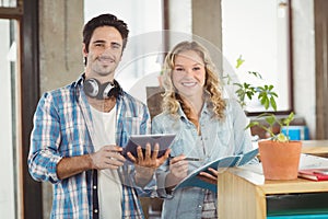 Portrait of happy business people holding digital tablet in creative office