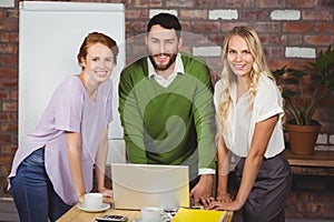 Portrait of happy business people leaning on desk