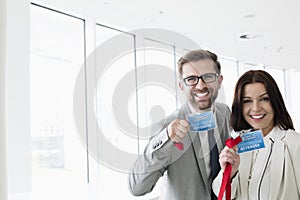 Portrait of happy business people showing identity cards in convention center