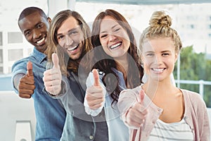 Portrait of happy business team with thumbs up while standing in row