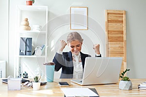 Portrait of happy business woman in office rejoicing success