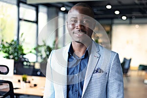 Portrait of happy businessman with arms crossed standing in office