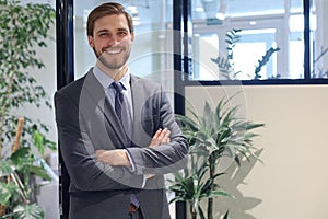 Portrait of happy businessman with arms crossed standing in office