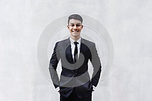 Portrait of Happy Businessman in Black Formal Suit. Standing by the Cement Wall