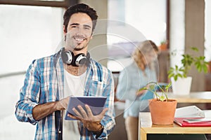 Portrait of happy businessman holding digital tablet creative office