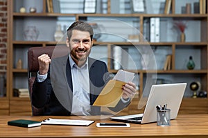 Portrait of happy businessman investor, mature adult man smiling and looking at camera, boss holding message envelope
