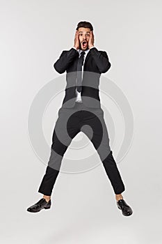 Portrait of a happy businessman jumping in air against isolated white background.