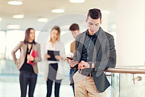 Portrait of happy businessman in office holding digital tablet