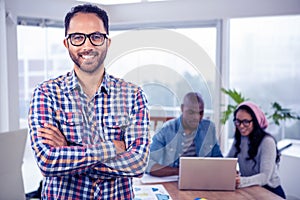 Portrait of happy businessman standing with arms crossed in office