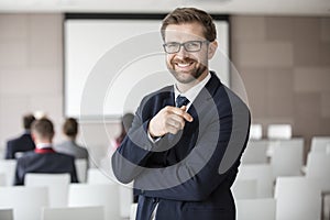 Portrait of happy businessman standing in seminar hall