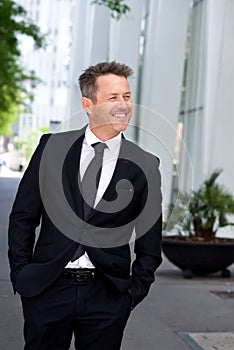 Happy businessman walking outside on sidewalk