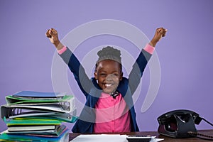 Portrait of happy businesswoman with arms raised at desk