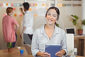 Portrait of happy businesswoman holding digital tablet in office