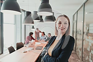 Portrait of happy businesswoman owner in modern office. Businesswoman smiling and looking at camera. Busy diverse team
